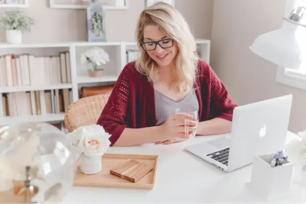 Chica en su oficina sonriendo con una taza de té en la mano con una sonrisa